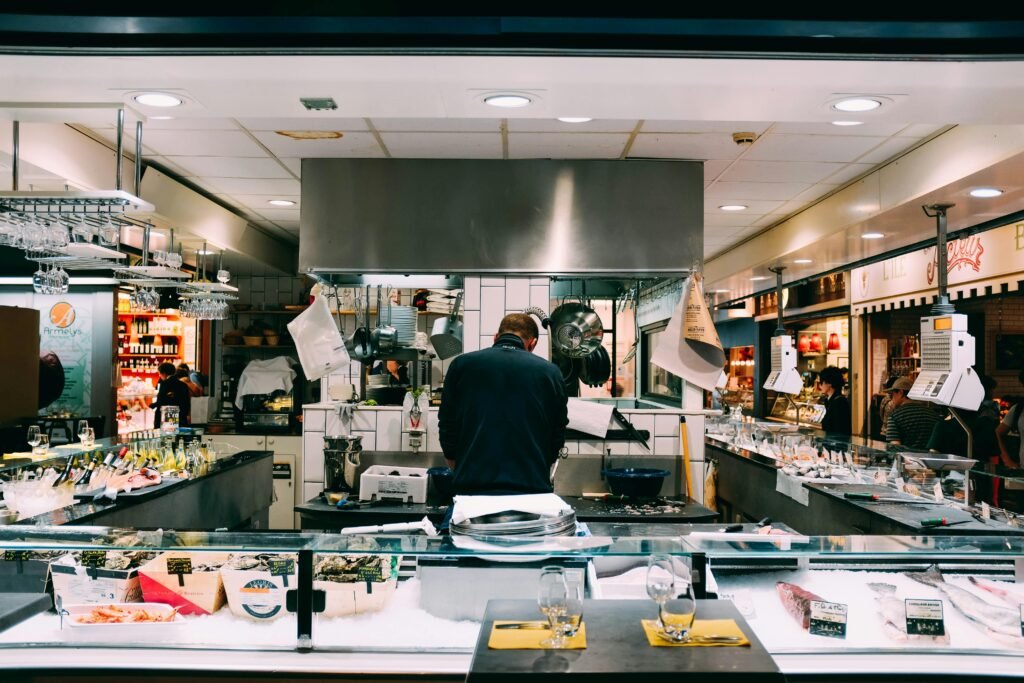 Chef preparing fresh seafood in a bustling indoor market setting.